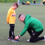 Turniej w Sokółce opiekun zawiązuje but małemu piłkarzowi.JPG